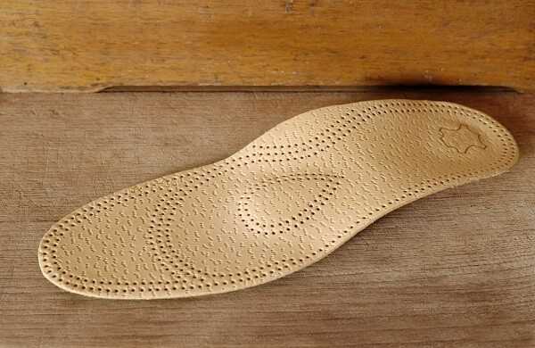 Orthopedic arch support made from leather on a wooden ground 1