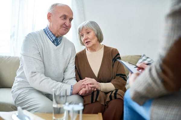 Portrait of nice senior couple holding hands visiting psychologist sharing problems in therapy session
