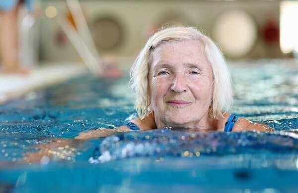 Happy healthy senior woman enjoying active lifestyle swimming in the pool