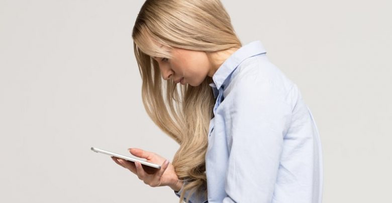 Close up portrait of young Caucasian woman looking and using smart phone with scoliosis