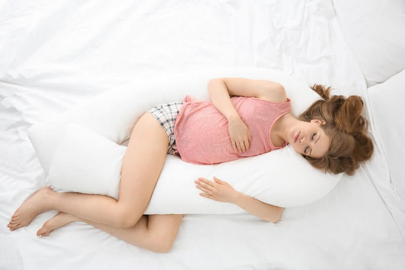 Beautiful pregnant woman sleeping with body pillow 