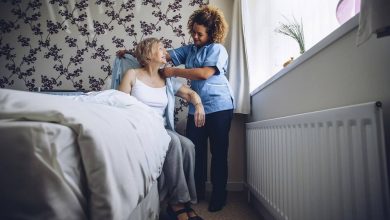Home Caregiver helping a senior woman get dressed in her bedroom