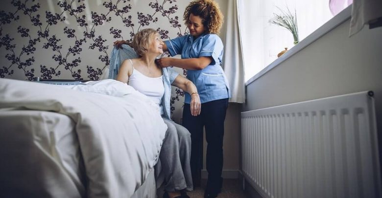 Home Caregiver helping a senior woman get dressed in her bedroom