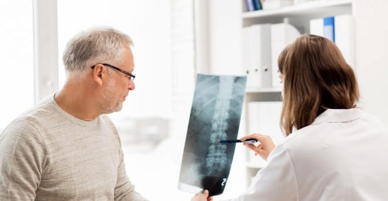 doctor showing x-ray of spine to senior man at hospital
