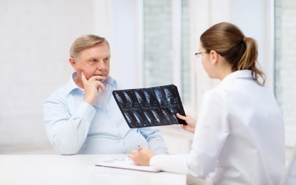 female doctor with old man looking at x-ray