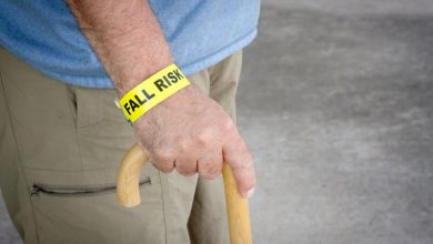 Fall risk bracelet around an elderly man's wrist while walking with a wooden cane