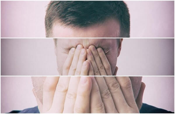 Young man covers his face with his hands in grief or pain